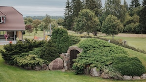 A house with a stone archway surrounded by lush greenery and a well-maintained lawn. - Klaara-Manni Holiday Center (Randivälja)