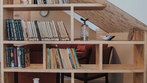 A wooden bookshelf with multiple shelves filled with books and a few decorative items. - Klaara-Manni Holiday Center (Randivälja)