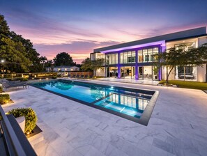 A modern building with a swimming pool, surrounded by a well-lit patio area.