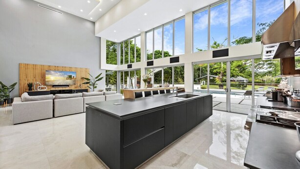 A modern kitchen with a large island, a dining area with a view, and a living room with a TV and seating. - Gated 9BR Estate for 20 w/ Private Pool, Jacuzzi, Theater & Guest House! Pet-Friendly! (Southwest Ranches)