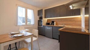 Une cuisine moderne avec des meubles gris, un plan de travail en bois et un four encastré.