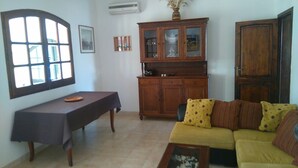 A living room with a sofa, a table, a cabinet, and a large window. - Villa Bellavista (Quartu Sant'Elena)