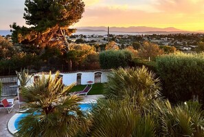 A pool area with lounge chairs and a view of a residential area and mountains in the background. - Villa Bellavista (Quartu Sant'Elena)