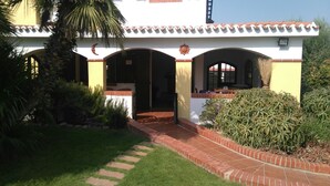 A building with a tiled roof, a covered patio area, and a brick pathway leading to the entrance. - Villa Bellavista (Quartu Sant'Elena)