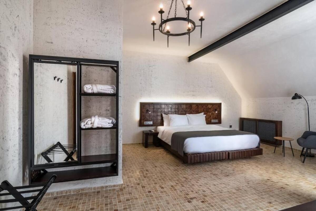 Ein modernes Schlafzimmer mit einem großen Bett, einem Kleiderschrank, einer Deckenleuchte und einem kleinen Tisch.