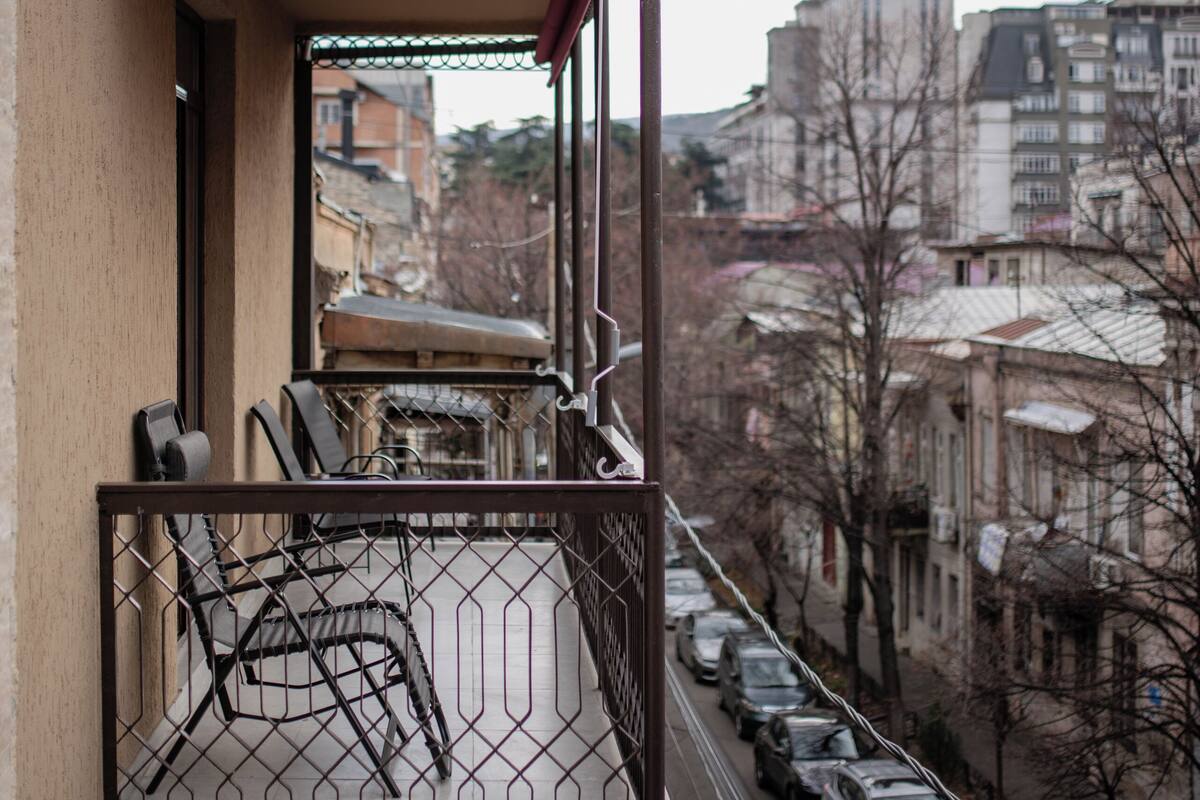 Ein Balkon mit Metallgeländer, einem Stuhl und einem Tisch.