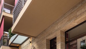 Der Eingang eines Boutique-Hotels mit einer Steinfassade, einem Schild mit der Aufschrift "KAZMA BOUTIQUE HOTEL" und einer Treppe, die zum Eingang führt.