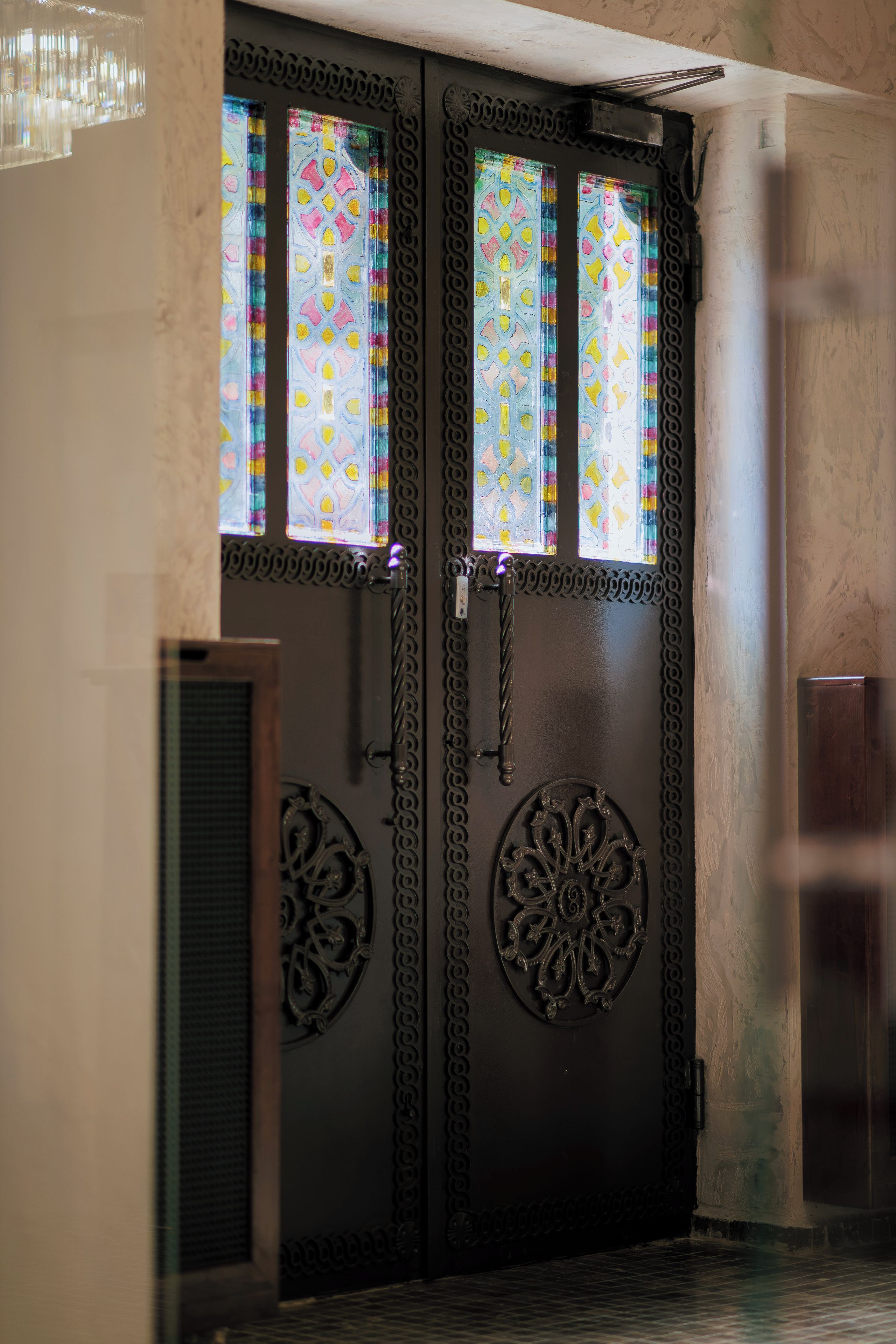 A double door with intricate metalwork and stained glass windows.