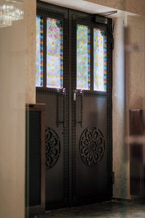 Une porte à deux battants ornée de motifs métalliques complexes et agrémentée de vitraux.