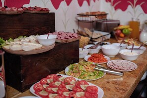 Ein Buffet mit verschiedenen Speisen, darunter Aufschnitt, Salate und Obst.