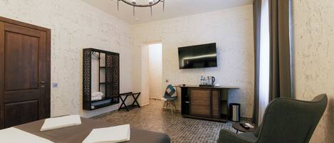 A hotel room with a bed, a TV mounted on the wall, a wooden cabinet, and a chair.