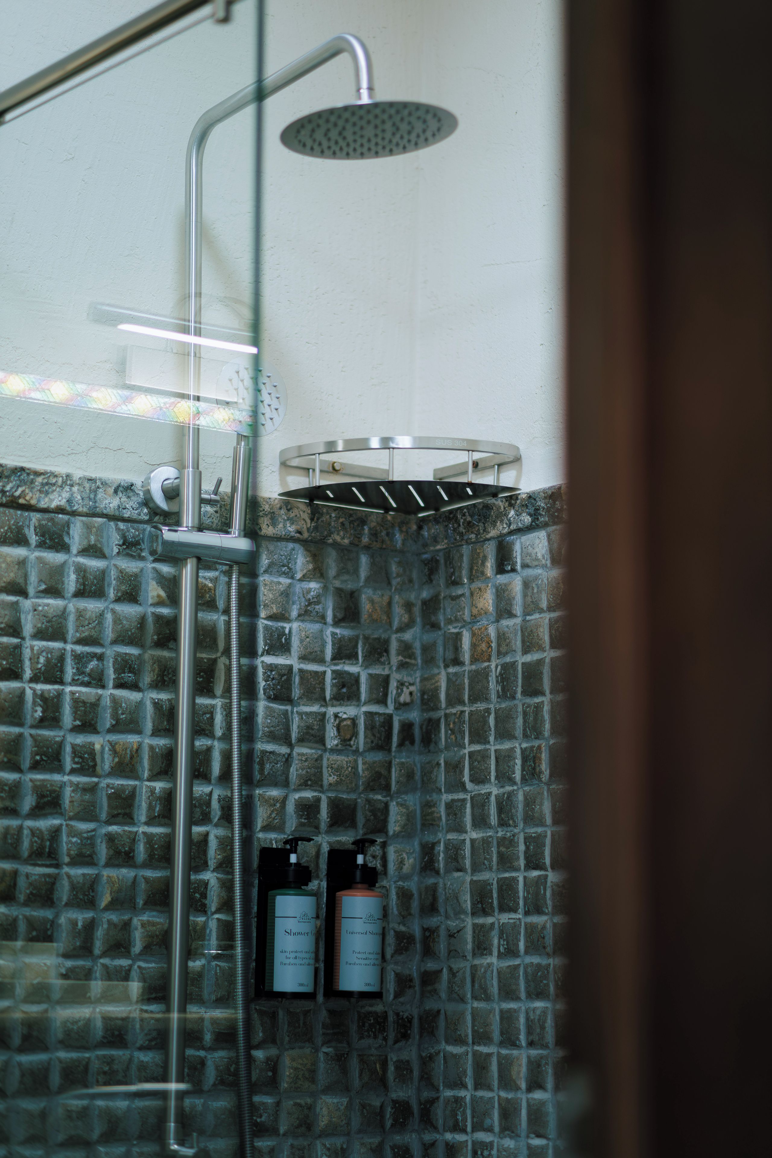 A shower area with a rain shower head, a handheld shower attachment, and two bottles of shampoo.