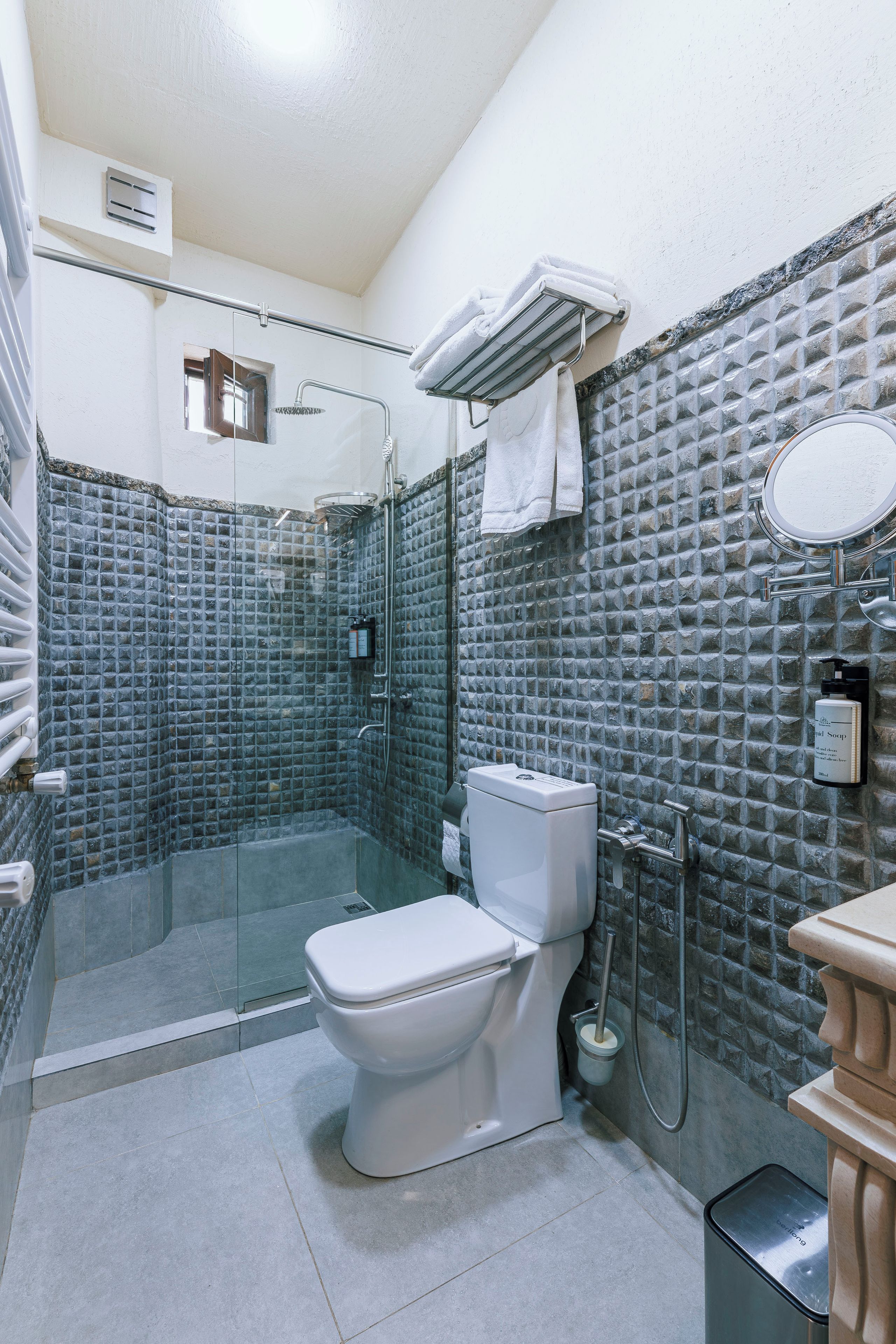 A bathroom with a glass-enclosed shower, a toilet, and a sink with a mirror.