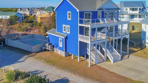 Een blauw huis met twee verdiepingen, een balkon en een jacuzzi.