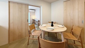 A dining area with a round table set for six, surrounded by wooden chairs. - Celine Kanayama 501 (Hiroshima)