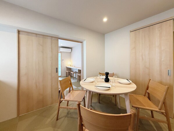 A dining area with a round table set for six, surrounded by wooden chairs. - Celine Kanayama 501 (Hiroshima)