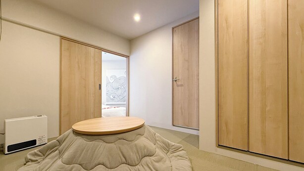 A modern room with a round, cushioned seating area, wooden wardrobes, and a radiator. - Celine Kanayama 501 (Hiroshima)