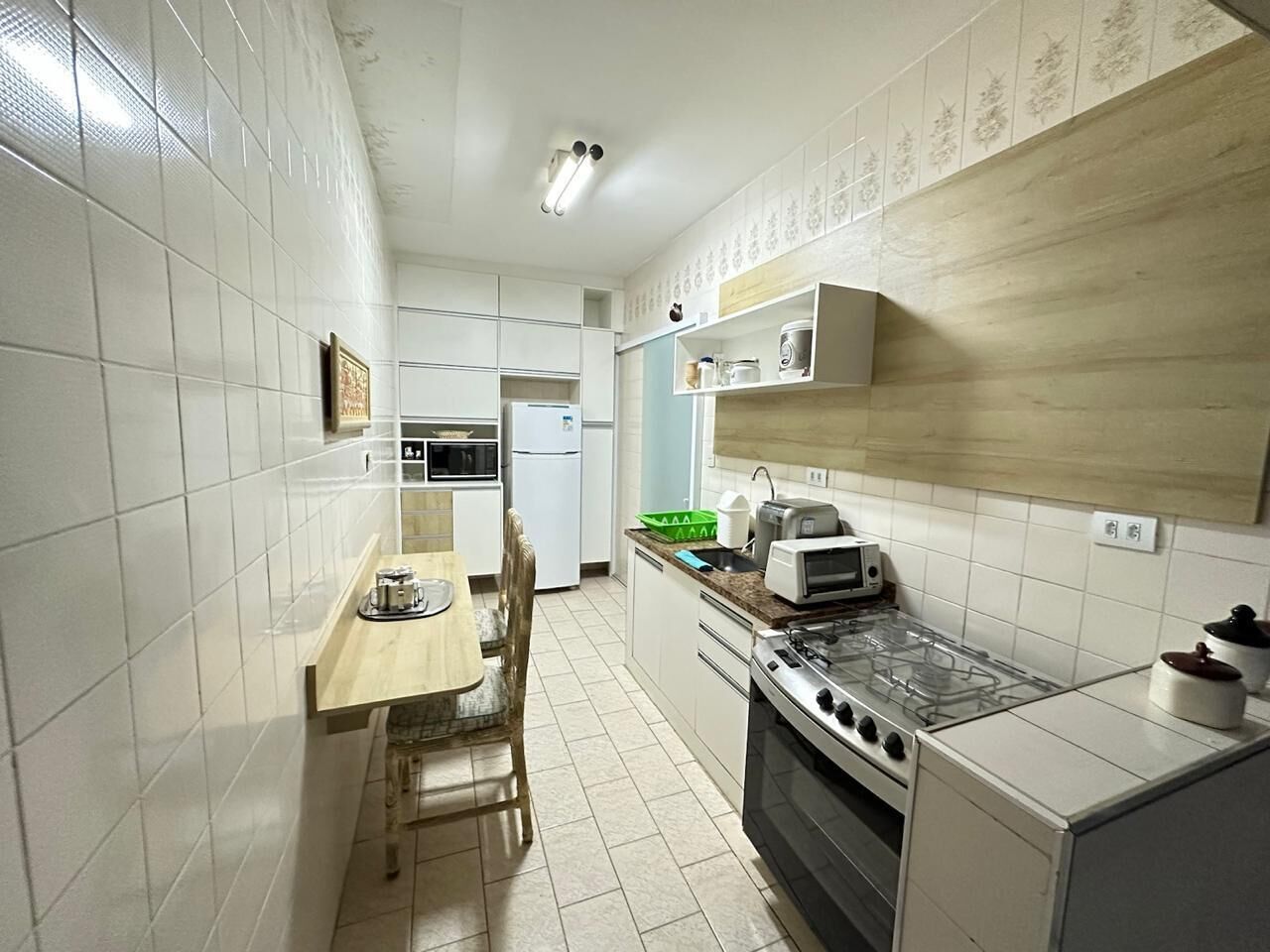 A compact kitchen with white cabinets, a gas stove, a microwave, and a dining area with a wooden table and chairs.