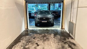 Eine Autowaschanlage mit einem grauen Auto in der Mitte, einem Metalldach und einem Betonboden.