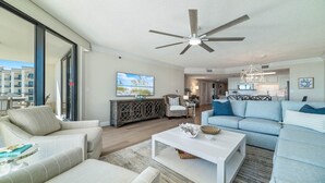 Een ruime woonkamer met een plafondventilator, een groot raam en uitzicht op de oceaan.