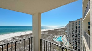 Een balkon met uitzicht op een strand en een zwembad.