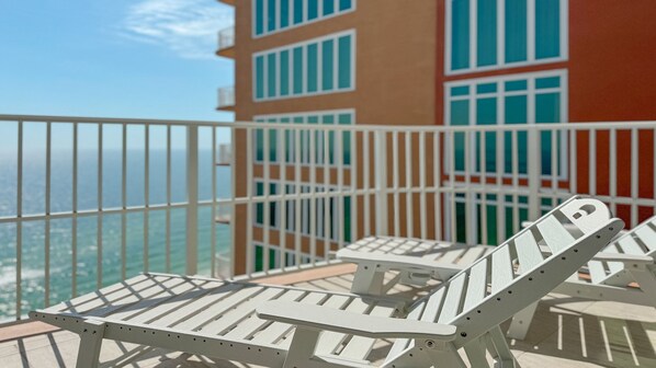Ein Balkon mit weißen Metallgeländern und zwei weißen Lounge-Sesseln.