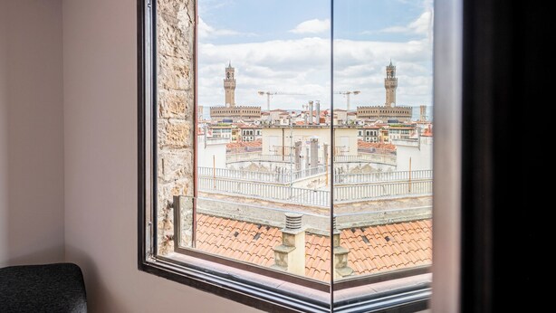 A room with a large window overlooking a historic cityscape with prominent towers and a plaza. - QUINTO -TOP VIEW OF FLORENCE (Florence)
