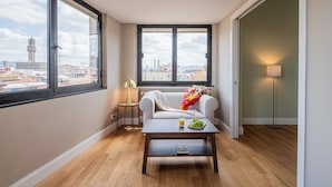 A room with a view of a cityscape, a sofa, a coffee table with a book, and a lamp. - QUINTO -TOP VIEW OF FLORENCE (Florence)