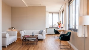 A modern living room with a sofa, a coffee table, and a chair. There is a window with curtains and a radiator. - QUINTO -TOP VIEW OF FLORENCE (Florence)