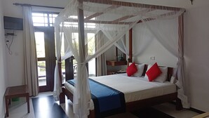 Ein Bett mit Baldachin, mit weißen und roten Kissen, einer blauen Tagesdecke und einem Holzkopfende.