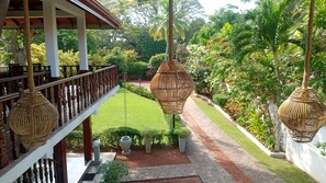 A balcony with a wooden railing, a stone pathway, and hanging wicker lamps. - Rockery Villa Ayurveda (Bentota)