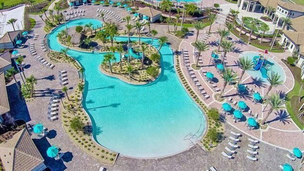 A large, winding pool with multiple sections, surrounded by palm trees and sun loungers. - Wonderland Sleeps 14 Free Waterparks and South Facing Pool (Kissimmee)