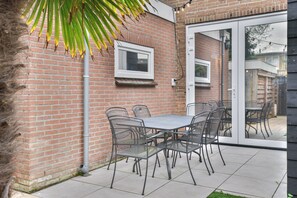 Eine Terrasse mit Backsteinmauer, Metallstühlen und einem Tisch.