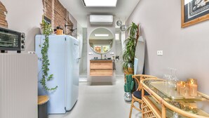 Une cuisine étroite comprenant un réfrigérateur, une cuisinière et un coin repas avec une table et des chaises.