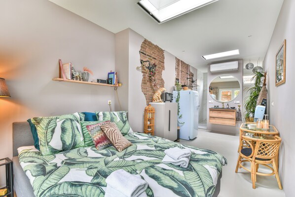 Ein modernes Schlafzimmer mit einem Bett, einem kleinen Schreibtisch, einem Spiegel und einem Kleiderschrank.