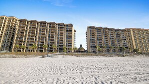 Een strandhotel met meerdere verdiepingen, balkons en palmbomen.