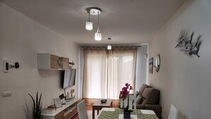A compact living space with a dining area, a sofa, a TV, and a window with curtains. - CT 362 AL First Line Beachfront Vera Playa ID 791 (Vera)