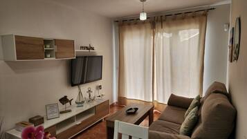 Una sala de estar moderna con un televisor de pantalla plana, estantes de madera, un sofá y una mesa de centro.