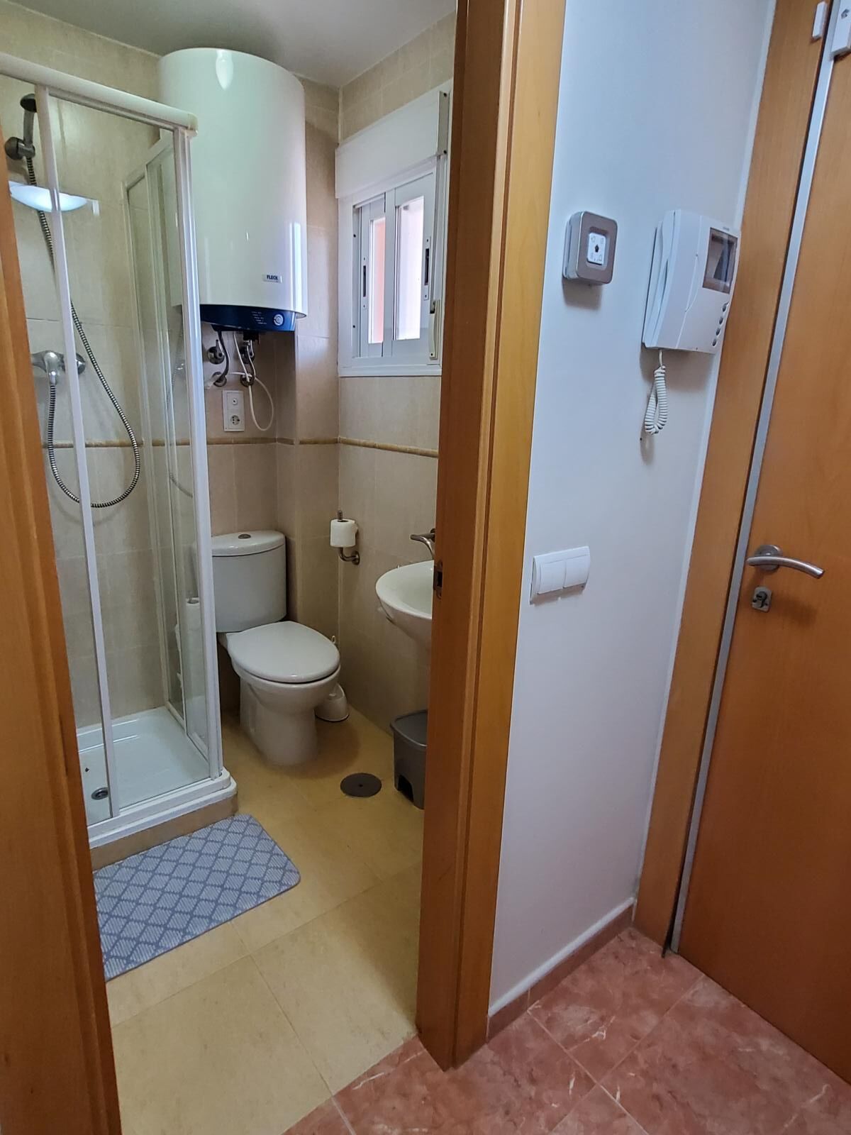Un baño pequeño con cabina de ducha de vidrio, inodoro y lavamanos.