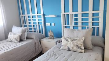 Una habitación con dos camas, un muro a rayas azul y blanco, y un adorno pequeño encima de las camas.