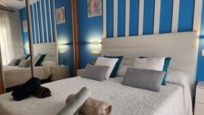 A hotel room with a large bed, blue and white striped walls, and a mirror reflecting the room. - CT 362 AL First Line Beachfront Vera Playa ID 791 (Vera)