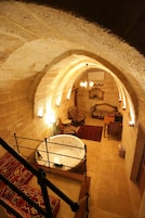 Interior de piedra con arco, que incluye una bañera, zona de estar y alfombras estampadas.