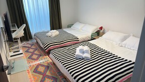 Habitación de hotel con dos camas, un televisor y un tapete colorido.