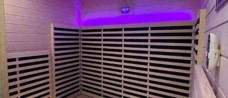 A sauna room with wooden slats, a bench, and ceiling lights.