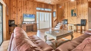 Un intérieur en bois avec un canapé en cuir, un téléviseur et un escalier.