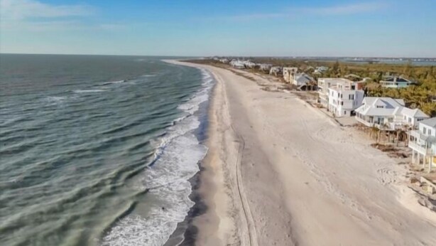 Une propriété située sur la côte, avec une plage de sable et vue sur l’océan.