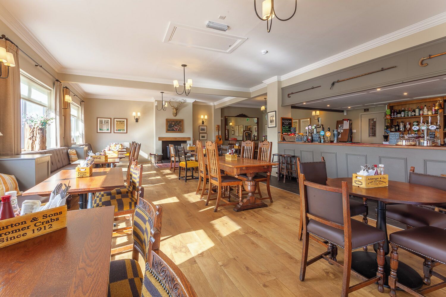 A restaurant with wooden tables and chairs, a bar area, and a fireplace.