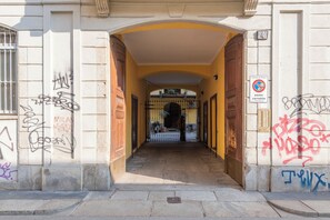 Entrada de un edificio con un arco amarillo, una puerta de metal y un cartel de no estacionamiento.