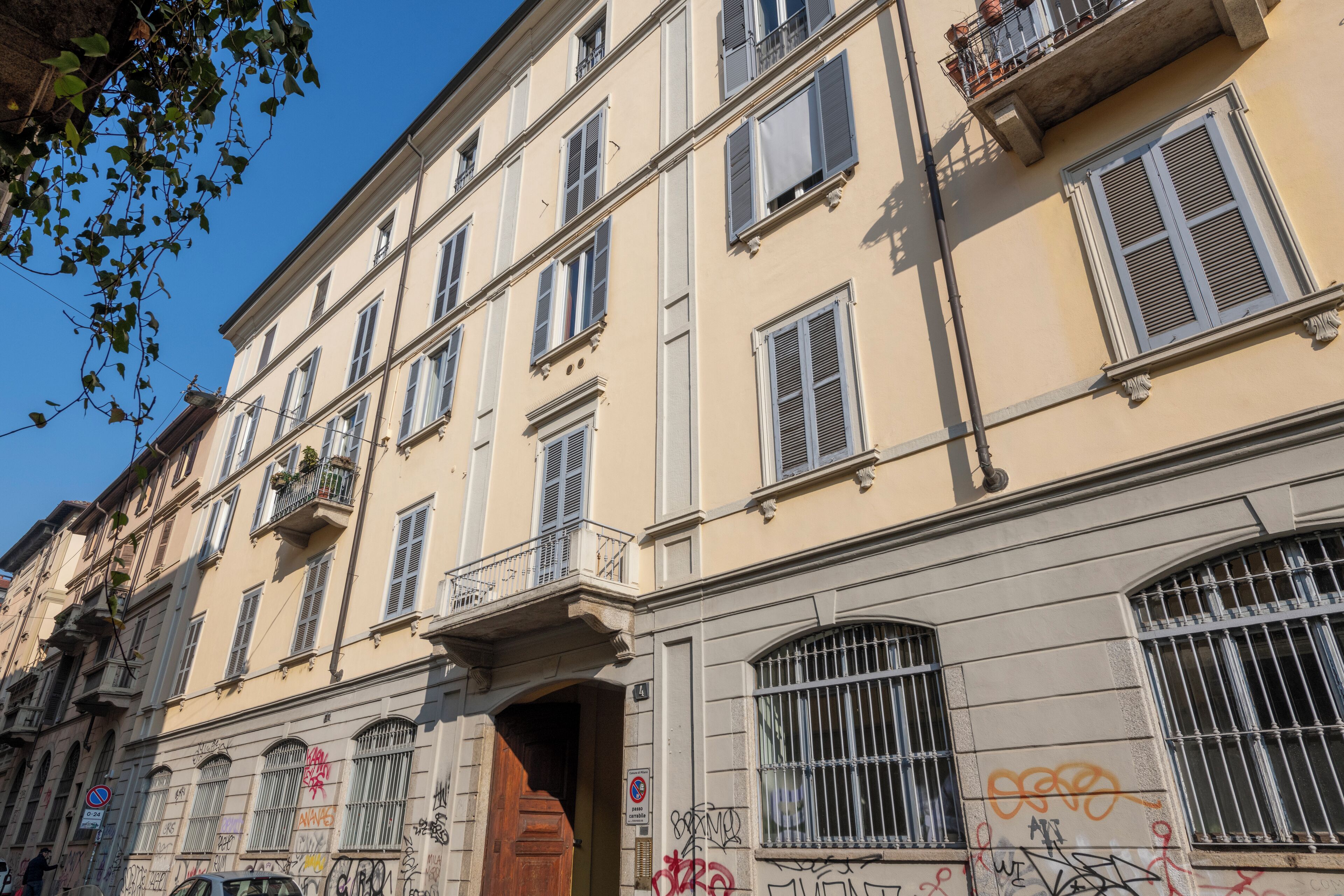 A multi-story building with balconies, barred windows, and graffiti.