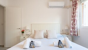 A hotel room with a bed, two bedside tables, an air conditioning unit, and a window with floral curtains. - MalagaSuite Terrace&Parking Stay Fuengirola (Fuengirola)